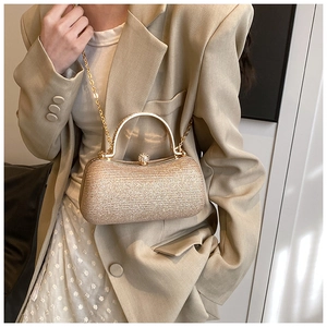 Detail of glitter gold box clutch bag with elegant metal handle and fine chain strap