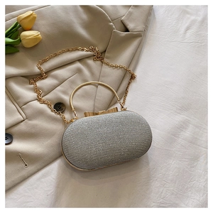 Close-up of a silver glitter evening clutch with gold handle and ribbon clasp
