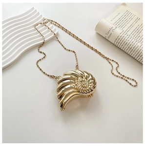 Detailansicht einer goldenen Abendtasche in Schneckenform mit eleganter Metallperlenkette
