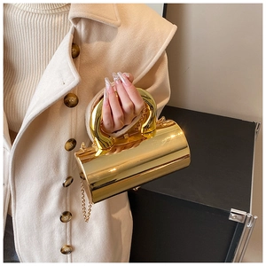 Vista detallada del bolso cilíndrico dorado brillante con su asa metálica de diseño exclusivo