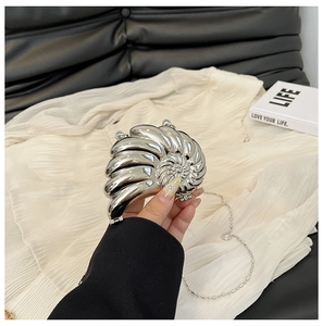Nahaufnahme der silbernen nautilusförmigen Clutch mit Spiraltextur und Metallkette