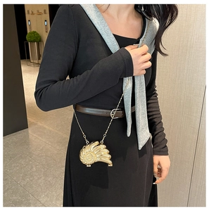 Goldene Abendtasche in Schneckenform mit Metallkette an einem weiblichen Model