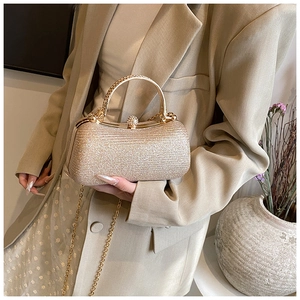 Detail of champagne gold glitter evening box bag with metal handle and pearl clasp