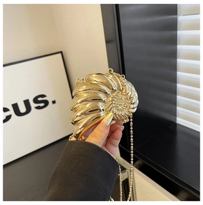 Detailaufnahme einer goldenen Abendtasche in Schneckenform mit feiner Metallperlenkette