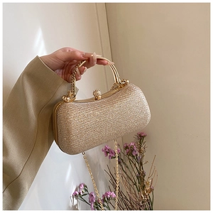 Detailed view of the gold sequined evening clutch with round metal handle and chain