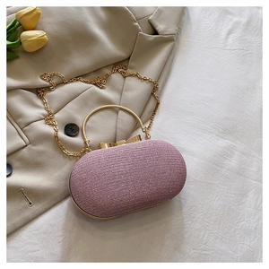 Detail of glitter evening clutch featuring a gold bow clasp and metal handle