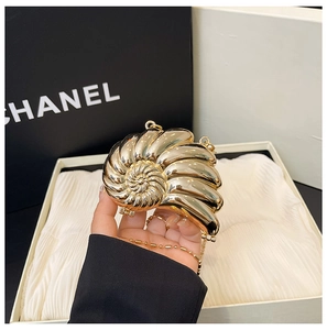 Makroaufnahme einer goldenen schneckenförmigen Abendtasche mit glänzendem Metall-Finish