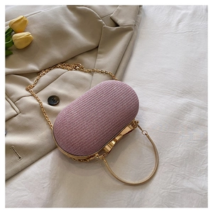 Detailed macro view of pink glitter clutch with gold handle and chain on beige fabric