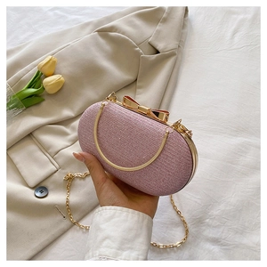 Detail of pink sequin clutch bag featuring a gold bow clasp and metallic chain strap