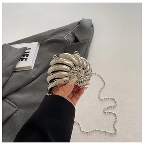 Detail einer silbernen Abendtasche in Schneckenform mit Metallkette und Spiegeleffekt