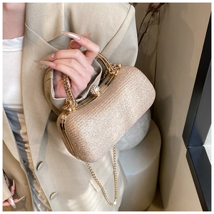 Close-up of gold glitter evening clutch with rhinestone handle and metal chain strap
