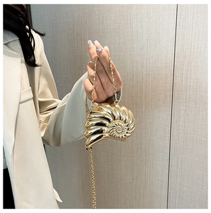 Detailaufnahme der goldenen Abendtasche in Schneckenform mit feiner Metallkette