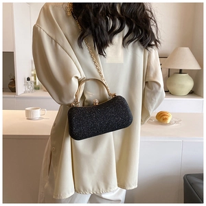 Detail of elegant black glitter evening clutch box bag with gold metal handle and chain
