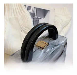 Detailed view of acrylic square bag featuring marble texture and golden metal clasp lock