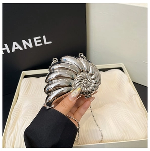 Detail der silbernen muschelförmigen Abendtasche mit poliertem Metallic-Finish und Perlenkette
