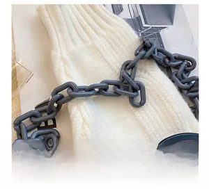 Detail showing grey matte acrylic chain strap on white thick knit fabric texture