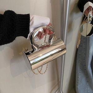 Elegante bolso cilindro plateado con efecto espejo y asa superior curva gruesa