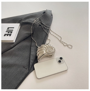 Makro-Detail der silbernen Nautilus-Abendtasche mit glänzendem Metall-Finish und Kette