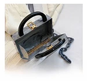 Detailed view of marble acrylic box bag with black handle and gold metal clasp
