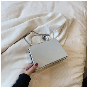 Detailed close-up of a silver mirror acrylic box bag with metal handle and chain strap