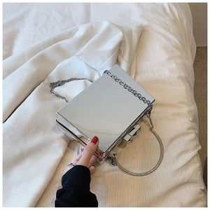 Close-up of silver mirror box bag with metallic chain strap and round top handle