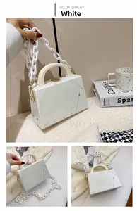Close-up of white marble pattern acrylic handbag with chunky chain and gold lock details