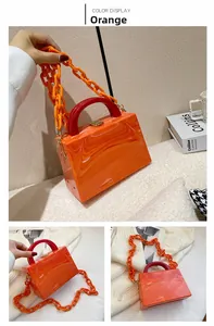 Detail view of orange marble texture acrylic handbag with chunky chain strap and gold clasp