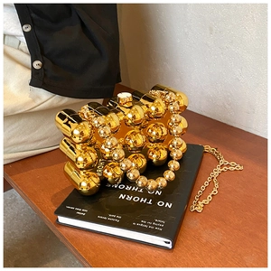 Artistic gold sphere evening bag with beaded handle and chain on an art book