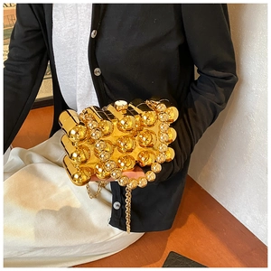 Detailed view of golden acrylic evening bag with 3D metallic spheres and pearl handle