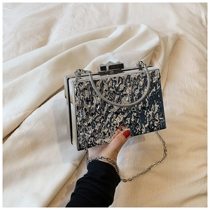 Detail of silver acrylic clutch bag with liquid ripple texture and metallic chain strap