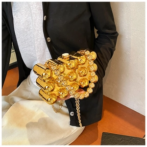 Close-up of golden geometric orb evening bag featuring metallic spheres and fine chain strap