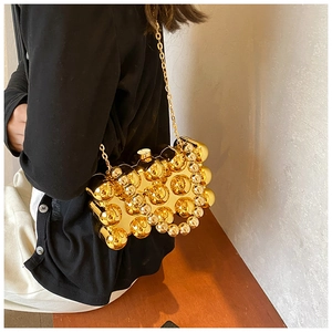 Detail view of the golden metal evening bag featuring 3D bubble texture and a fine chain