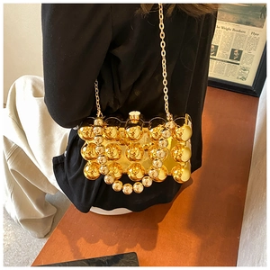 Detail of a structured gold acrylic evening bag with large 3D spherical studs and chain
