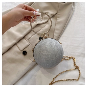 Détail d'un sac de soirée sphérique argenté avec poignée en strass et chaîne