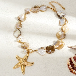 Macro detail of seashell choker with golden starfish pendant and iridescent pearls