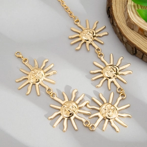Detail of golden sun face pendants on a metal waist chain with a lobster clasp closure