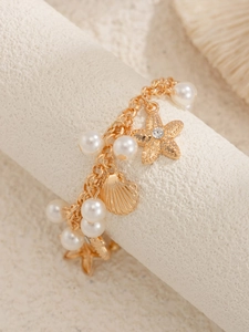 Detail view of gold starfish and shell charms with faux pearls on bohemian anklet chain
