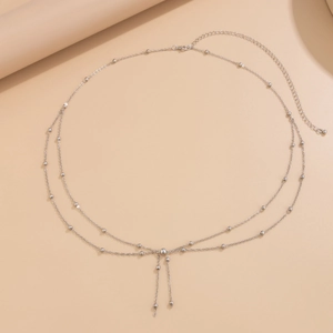Detail of silver double-layer waist chain featuring beads, tassels, and lobster clasp