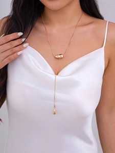Detalle de collar elegante en forma de Y dorado con colgante de metal y gota charm
