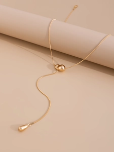 Detalle del collar en Y dorado con pasador de corazón fluido y colgante de gota