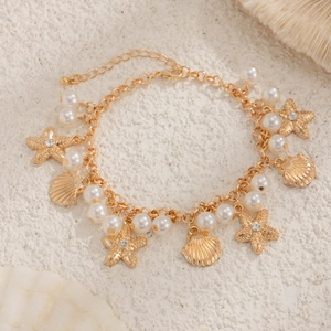 Bohemian gold starfish shell pearl anklet set on a beach sand background