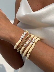 Dettaglio di braccialetti bohémien sovrapponibili con lettere LOVE MAMA e perline