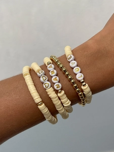 Dettaglio di braccialetti boho a strati con scritte Mama e Love sul polso della modella