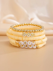 Dettaglio macro di braccialetti boho con ciondoli a lettere LOVE e MAMA dorati