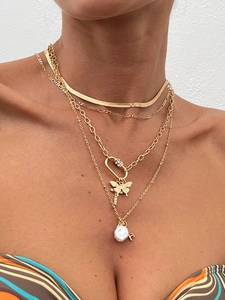 Close-up of layered gold necklace featuring butterfly pendant and baroque pearl charms