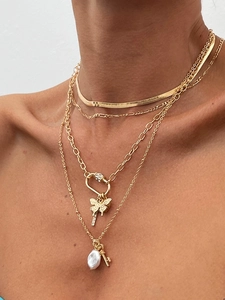 Detail of layered gold necklace set with butterfly, key pendants and pearl accent