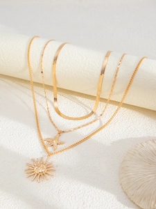 Detail of layered gold necklaces with starfish and sun pendants on white display