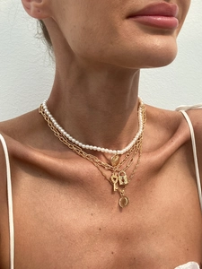Close-up of layered gold tone necklaces with heart lock and coin pendants on model