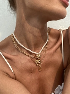 Detail of layered gold necklace set with heart pendant, key charm, and white pearls