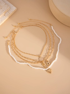 Detail of four-layer gold necklace set featuring pearl strands and heart lock pendants
